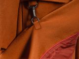 the back of a brown coat with a red lining and a metal clasp