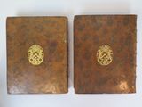two old books with gold medallions on them sitting on a white surface