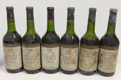 six bouteilles de vin sont alignées sur une surface blanche