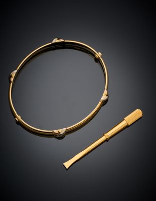 a gold bangle and a wooden stick on a black background
