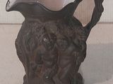 un petit vase marron muni d'une anse, posé sur une table