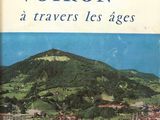 an old book with a picture of a town and a mountain in the background