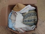 une boîte remplie de vêtements et un chapeau par terre
