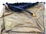 a gold purse with a black fur inside of it
