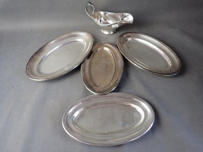 four silver plates and a creamer sitting on a table