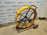 a close up of a yellow hose on a cart in front of a wall