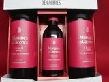 three bottles of red wine in a pink box on a red background