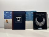 three books on a white table with a blue sky and clouds in the background