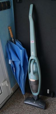 un aspirateur posé par terre à côté d'un parapluie bleu