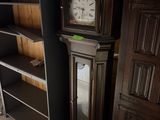 une horloge de parquet dans un coin de la pièce, à côté d'une bibliothèque