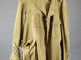 an old jacket hanging on a hanger on a gray wall