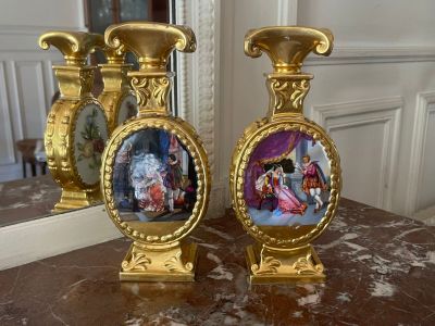 two gold vases with pictures on them sitting on a table