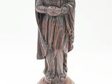 une vieille statue représentant une femme tenant un enfant dans ses bras, posée sur un socle en bois