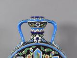 a blue and black vase with a floral design on it