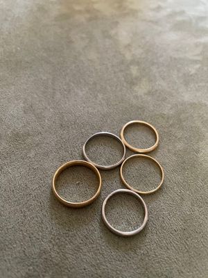 cinq bagues en or et en argent sur un fond gris