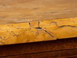 a close up of a piece of yellow paint on a wooden table