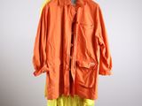 une veste orange suspendue à un cintre devant un mur blanc