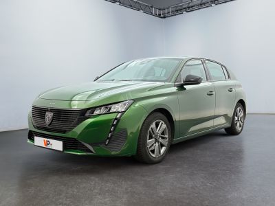 La voiture verte est garée dans une pièce blanche au sol noir.