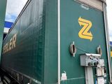 a green semi truck with a yellow z logo on the side