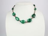 un collier avec des perles vertes sur un mannequin blanc