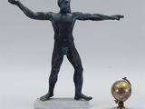 a statue of a man holding a globe next to a statue of a man