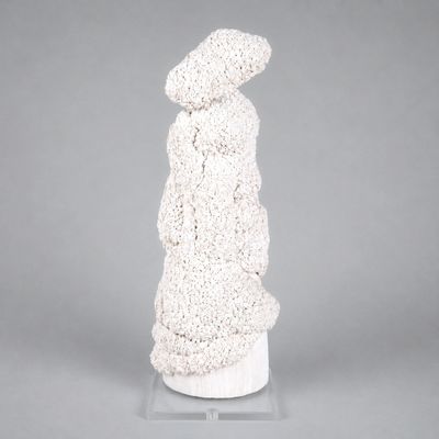une sculpture blanche représentant une femme debout sur un socle blanc