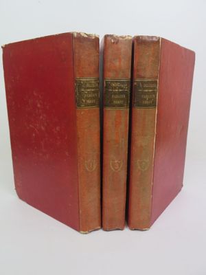 trois livres rouges superposés sur une surface blanche