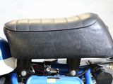 a blue motorcycle with a black seat and a white helmet
