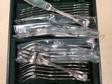 six forks and a knife in a case on a table