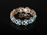 un gros plan d'un bracelet orné de pierres turquoise sur un fond noir