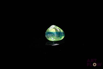 a close up of a green and white diamond on a black surface