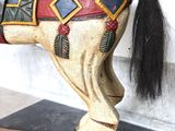 a wooden horse that is standing on a black and white checkered floor