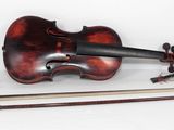 un vieux violon est posé sur une surface blanche, à côté d'un archet