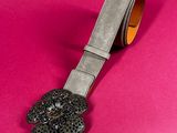 a close up of a belt with a flower on it on a pink background