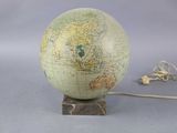 un globe terrestre posé sur un socle, auquel est attaché un cordon
