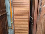 une grande armoire en bois dont la porte est ouverte, dans une pièce