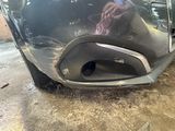 a close up of a car ' s bumper with a hand on it
