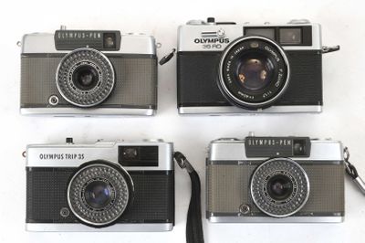 four cameras are lined up in a row on a white surface