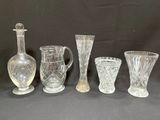 five glass vases and a decanter sitting on a table