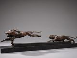 two bronze sculptures of a dog and a cat running on a marble base