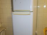 a white refrigerator sitting in a kitchen next to a yellow chair