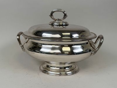 a silver plate with a lid and handles on a white surface