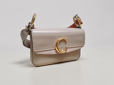 a small beige purse with a gold ring on the handle