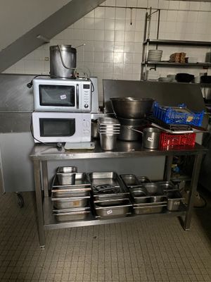 une cuisine où de nombreuses casseroles et poêles sont posées sur le plan de travail