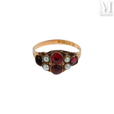 a close up of a gold ring with a red stone and pearls