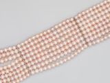 a close up of three rows of pink pearls on a white surface
