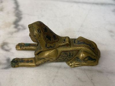 figurine en laiton représentant un chien couché sur une surface en marbre