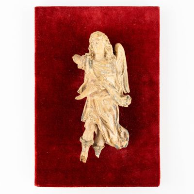 an antique carved ivory figurine of an angel on a red velvet surface