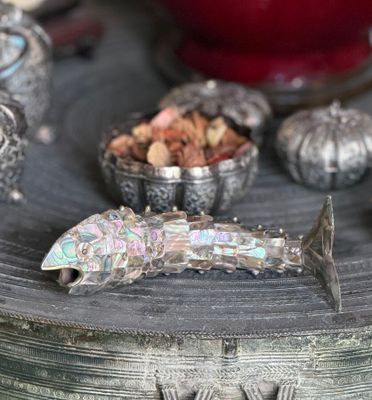 a silver fish sitting on top of a table next to other silver objects