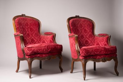 paire de fauteuils rembourrés rouges avec des pieds en bois sculpté